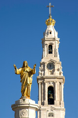 Obraz premium The bell tower of the Sanctuary of Fatima rises towards a clear blue sky