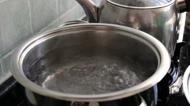 Homemade soup. Salt and orzo are added to boiling water in a pot.