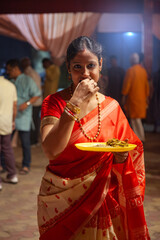 Traditional Bengali Woman Enjoying Bhog During Kali Puja Celebration in Red Saree