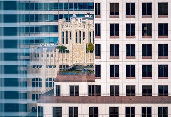 Obraz premium A striking urban scene featuring a sleek modern high-rise with a grid of windows juxtaposed against an ornate historic cathedral with gothic-style arches and intricate details. 