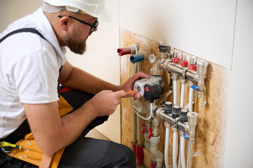 Man adjusting the heating system in a new apartment. Plumber adjusting heat on the central system...