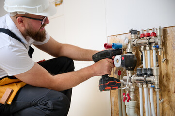 Man adjusting the heating system in a new apartment. Plumber adjusting heat on the central system valves. Service man adjusting house heating system. Underfloor heating system. Man checking pipe