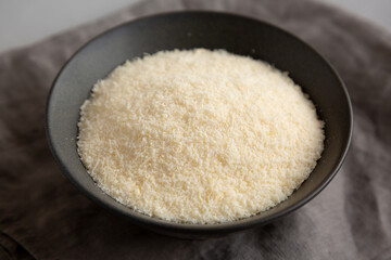 Organic Parmigiano Reggiano Parmesan Cheese Grated in a Bowl, side view.
