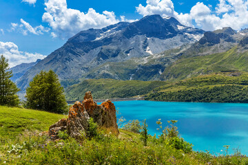 Picturesque view of a turquoise water of Mont Cenis lake surrounded by green slopes and mountains in France.