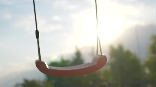 Empty swing in park at sunset, gently swaying in breeze. Peaceful playground scene invites fun and play. Swing awaits kids for joyful playtime in park carefree fun. Perfect spot for play fun in park.