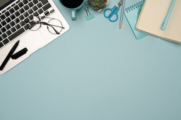 Creative workspace with laptop, glasses and office stationery on pastel blue background