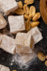 Turkish delight on the table, sugar cubes with starch and toasted peanuts on a black surface