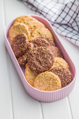 Sweet oatmeal cookies in bowl on white table.