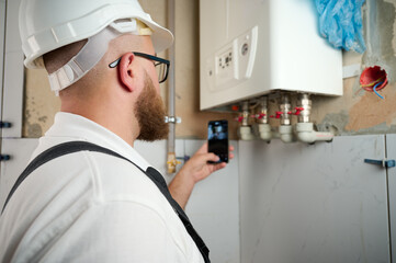 Plumber Install a Boiler. Professional engineer installing gas boiler at home and checking the connections and pipes of the domestic heating system. Boiler Installation 