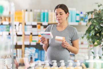 Focused pregnant woman choosing pill box and making decisions about pharmaceuticals and health care...