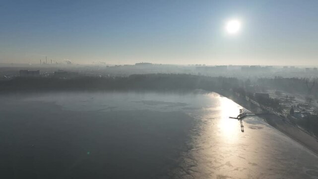 Steelworks in the fog. Frozen lake in the morning fog on a sunny day. Pogoria lake in winter, Dabrowa Gornicza, Poland. Ice shrouded lake in fog aerial shot from a drone.