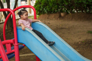 Naklejka premium happy toddler baby girl sliding and playing at playground