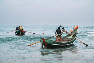 Naklejka premium Vietnamese fishermen men on traditional boats in sea at fishing village in Vietnam