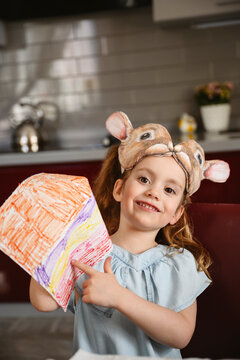 Girl with bunny mask painting in the kitchen
