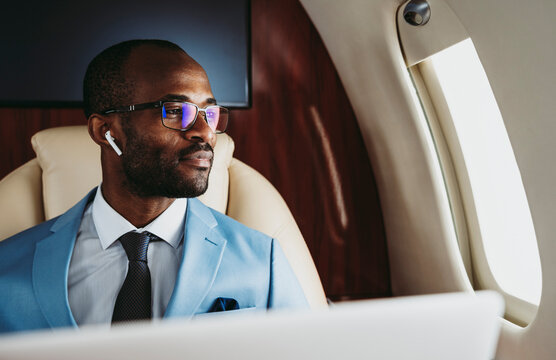 Smiling businessman looking through window in private jet
