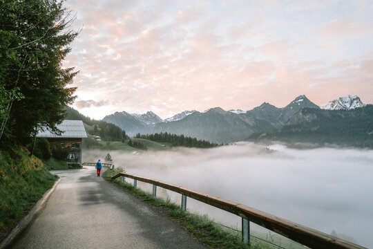 Wanderer bei Sonnenaufgang in den Alpen mit Nebel im Tal und Schnee auf den Bergen