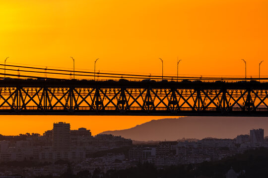 Impressive sunset silhouettes bridge over city skyline with vivid