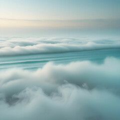 Fototapeta premium A tranquil teal ocean meets the horizon as a glowing fog bank slowly rolls in, bathed in warm late-morning sunlight and swirling mist.