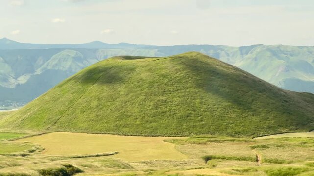 Beautiful scenic landscape of Komezuka volcanic cone, slow panning shot of the green hill in Mount Aso, Kyushu, Japan.