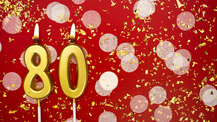 Golden burning candle number digit eighty. Birthday greeting card with inscription 80 on red background with confetti and glitter. Anniversary, celebration event and birthday