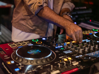 Close-up of a DJ’s hand mixing on a professional DJ controller during a live performance —...