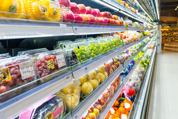 Supermarket fruit refrigerated section with rows of packaged fresh fruits including grapes, apples, mangoes and pears, showcase freshness, convenience and healthy eating. Food retail in grocery store