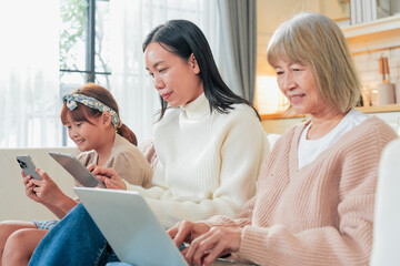 Asian family with smartphone game online technology Grandmother learning new technologies with granddaughters using smartphones at home Laughing intergenerational family spending leisure time	