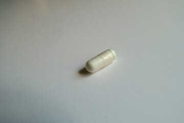 Closeup of one white capsule of acetyl cysteine dietary supplement