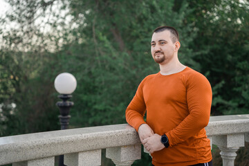 A man in workout clothes rests on a railing with a scenic view