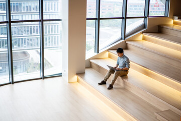 asian businessman working on laptop on staircase