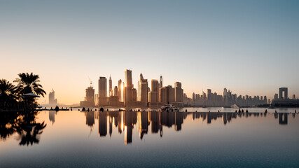 the skyline of the reflected dubai marina during sunrise
