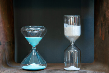 Two Hourglasses Measuring Time on a Metal Shelf