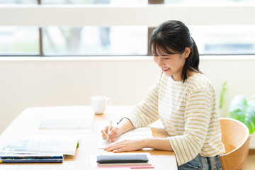 部屋で勉強をする大学生の女性