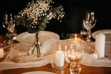 A delicate bouquet of flowers, candlelight and the wooden texture of the table create a romantic atmosphere. Table decoration.