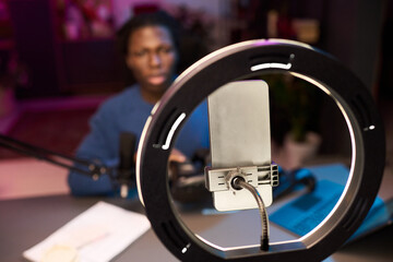 African American man recording himself speaking into microphone with ring light and smartphone...
