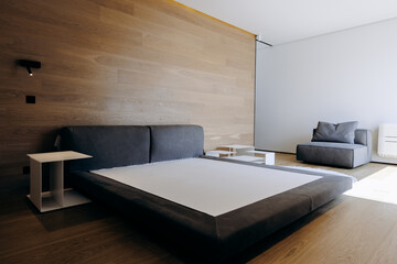 A bed is in the middle with a wooden wall behind it