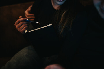 A close-up image of a hand holding a pen and a black notebook, suggesting planning or note-taking...