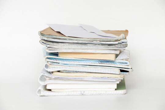 A stack of old notebooks, notepads and books on a white background, a symbol of study, education and work
