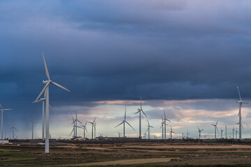 Wind turbines in Zaragoza field under moody sky, renewable energy landscape, ideal for green energy, sustainability, and environmental stock themes.