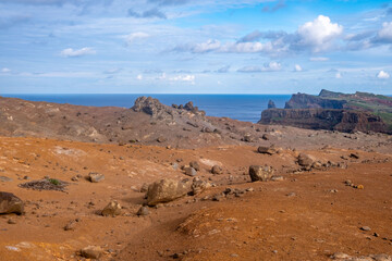 Martian-like landscape on Madeira, arid beauty Madeira's volcanic terrain, Red earth, scattered rocks, and ocean view, unique hiking experience, desolate landscape, archipelago beauty