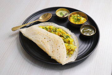 Crispy Masala dosa is a popular South Indian food item served with tomato chutney, coconut chutney, spicy potato masala, or aloo ki sabzi and sambar. Copy space. Crunchy Rice crepes.