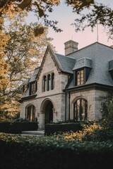 Fototapeta premium Elegant stone mansion surrounded by lush greenery at sunset highlights architectural beauty and serene environment in a tranquil neighborhood
