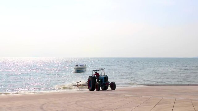 Tracktor pulls boat out of the water on beach Thailand.