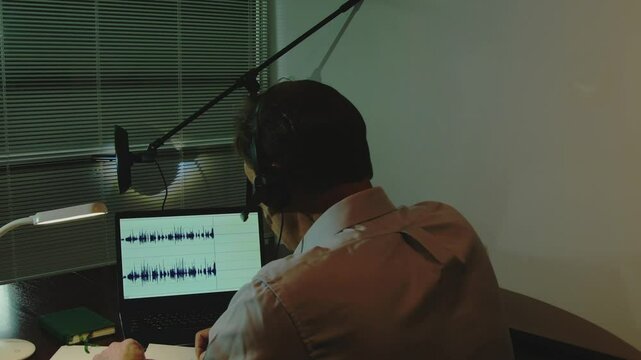 The concept of cyber espionage and surveillance is a laptop with audio waves and a man with headphones in the penumbra.