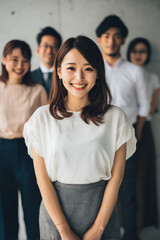 Obraz premium A young adult Japanese woman takes team photos for a company website refresh, capturing natural smiles and authentic moments of collaboration. Her approach strengthens corporate identity