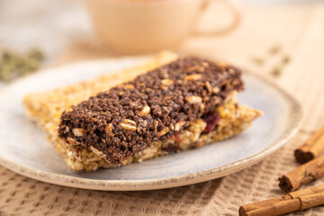 granola bars with caramel, nuts, flakes in ceramic plate on brown concrete. Side view, selective focus.