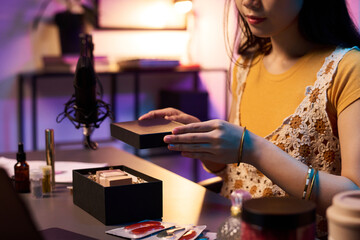 Fototapeta premium Asian woman presenting makeup tools for beauty routine while sitting at a desk. Various cosmetics and brushes during advertising livestream on social media