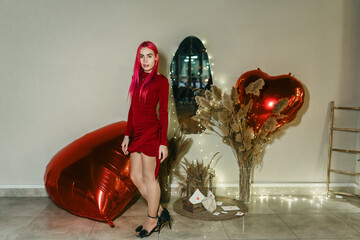 A woman in a red dress holding a giant inflatable Valentine's Day heart in her hands