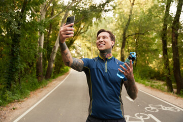 Handsome young man enjoying a walk while taking a selfie in a vibrant park setting
