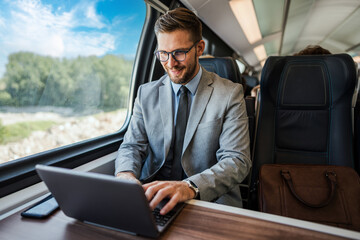 Handsome businessman working on a laptop during a train journey, utilizing technology for productivity on the go